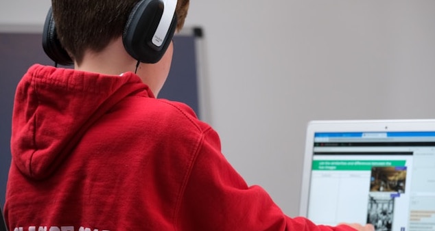 Image of student wearing headphones and working on a notebook computer. Skill sets for school IT.