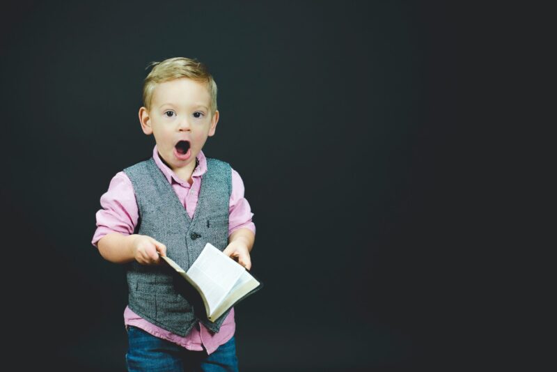 Image of a schoolboy holding a book, his mouth wide open in amazement.