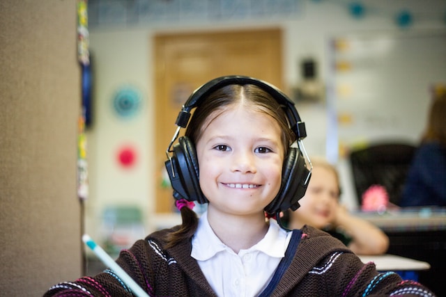 Image of a smiling student, wearing a pair of headphones.