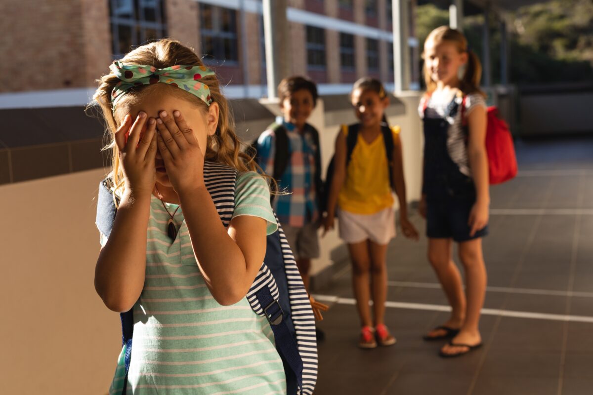 School friends bullying a crying girl in hallway of elementary